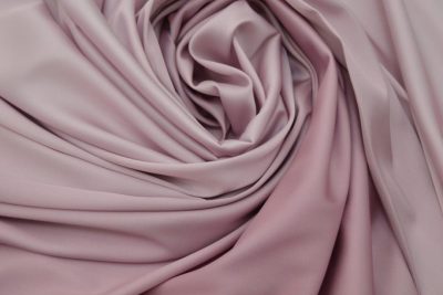 Elegant draped fabric in a soft rose pink shade, creating smooth folds and a luxurious texture.